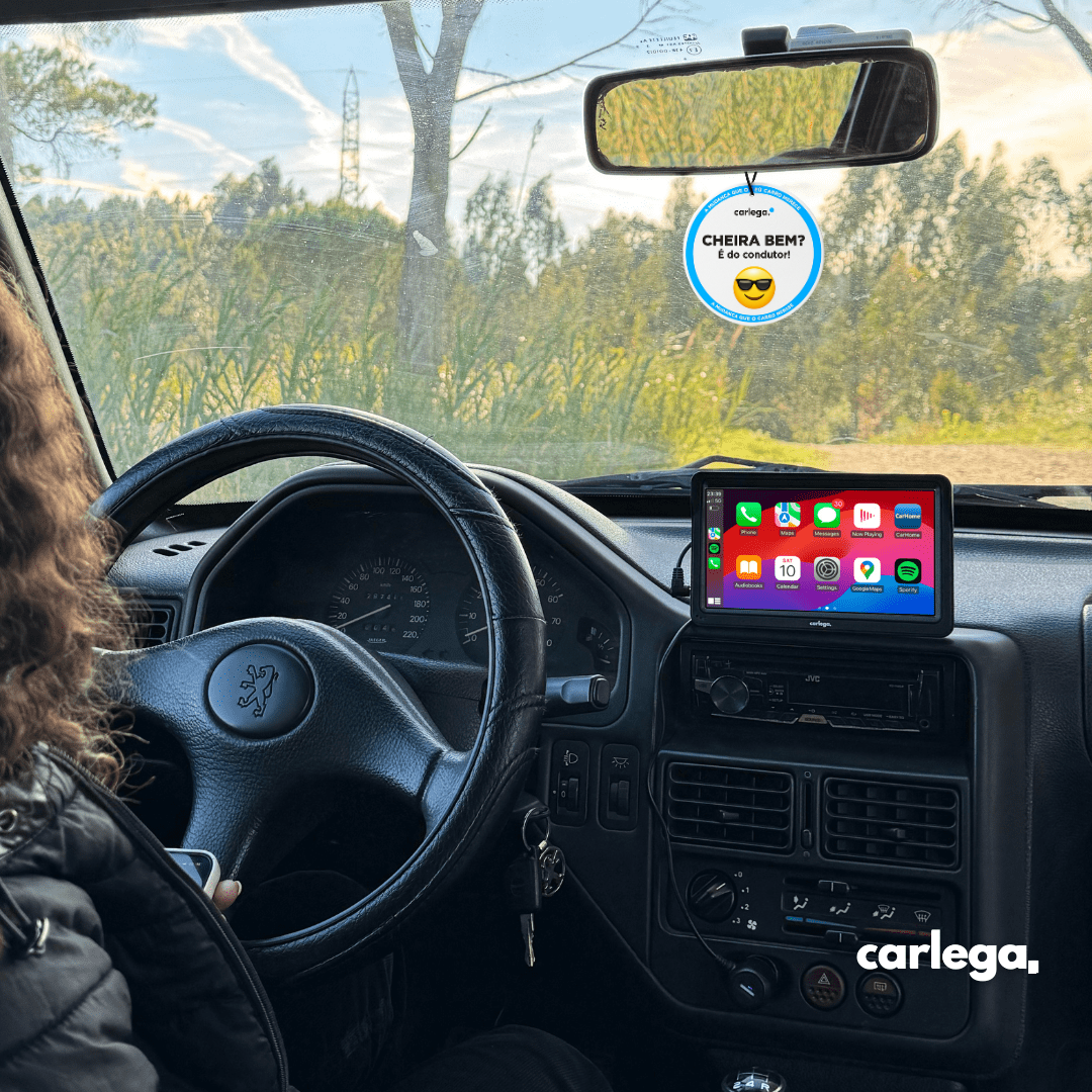 Condutora ao volante de um Peugeot com o ecrã Carlega X no tablier e o ambientador no retrovisor
