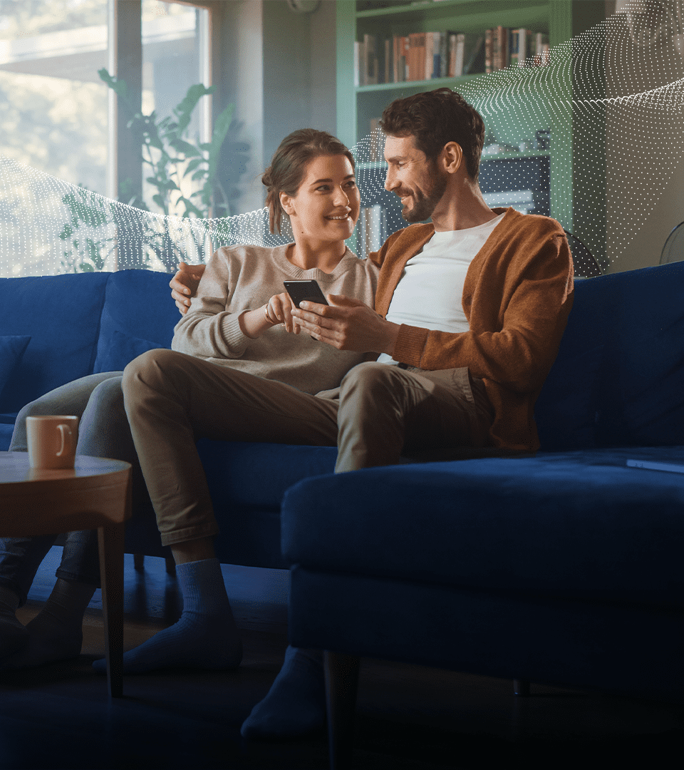 Casal sentado no sofá a ver o telemóvel, na página do programa de afiliados da Carlega