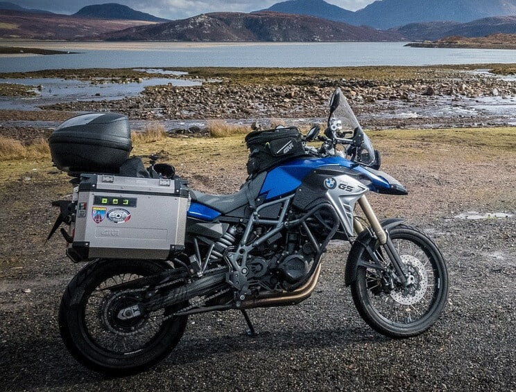 Ecrã BikePlay instalado numa mota BMW GS de viagem, parada junto a um lago