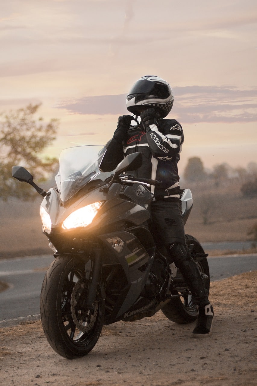 Motociclista numa mota desportiva ao pôr do sol, com o farol aceso