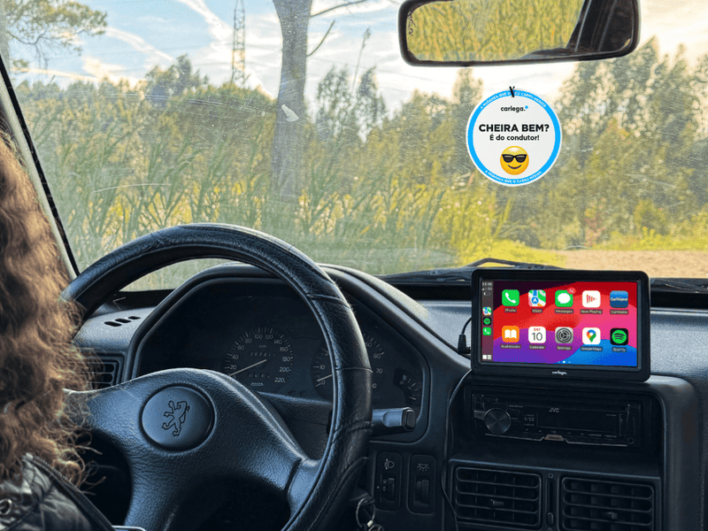 Ambientador Cheira Bem da Carlega pendurado no retrovisor de um Peugeot, com o ecrã ligado no tablier