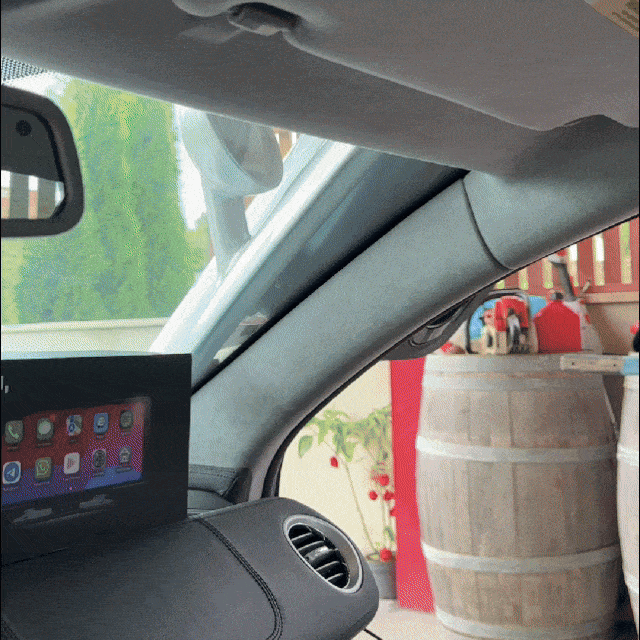 Ecrã Carlega montado no tablier de um carro, com um barril de madeira ao fundo