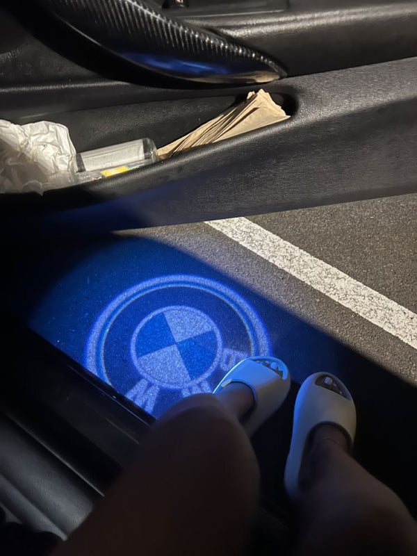 Logótipo da Volkswagen projetado a azul no chão, pela porta aberta de um carro